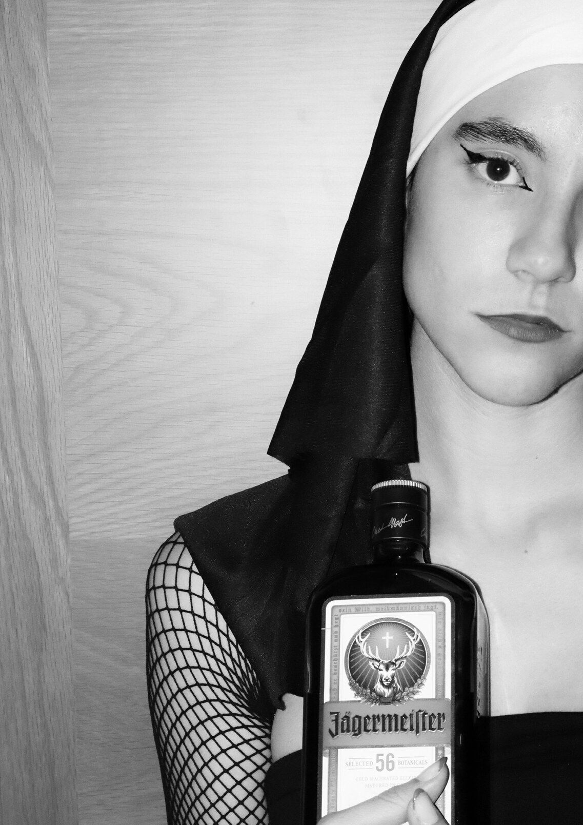 Chica vestida de monja con medias de rejilla sujetando una botella de Jägermeister