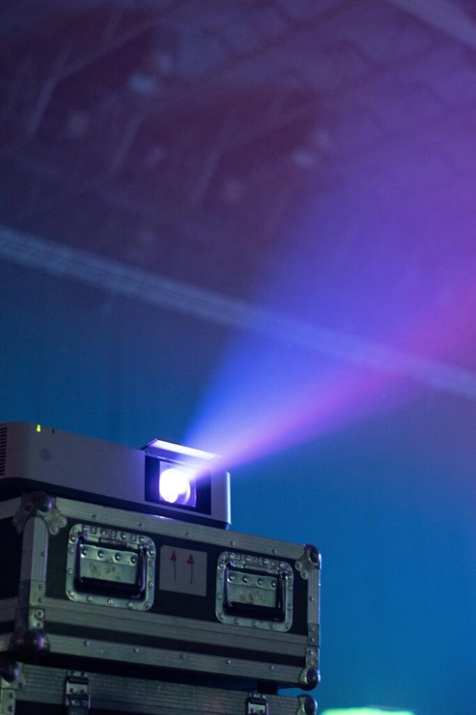 Vibrant light beam projecting from a stacked projector case in a dark room.